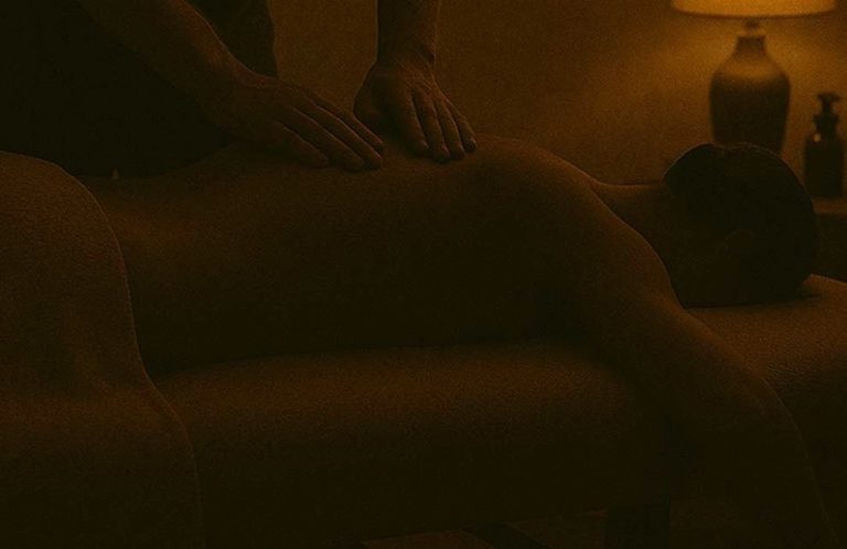 Eine Person erhält eine ruhige Rückenmassage in gedämpftem Licht.