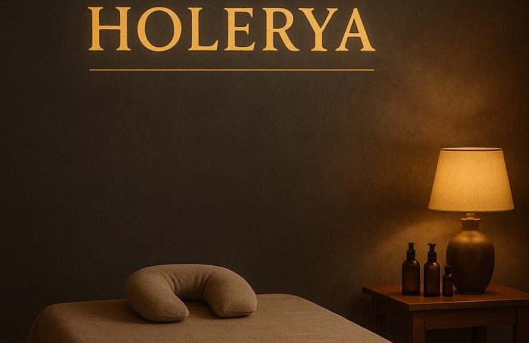 Raum mit entspannter Atmosphäre, Holerya-Schriftzug, Lampenlicht und Massagezubehör.